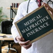 A physician holding a sign saying "medical malpractice insurance"