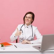 Woman doctor giving thumbs up while using computer